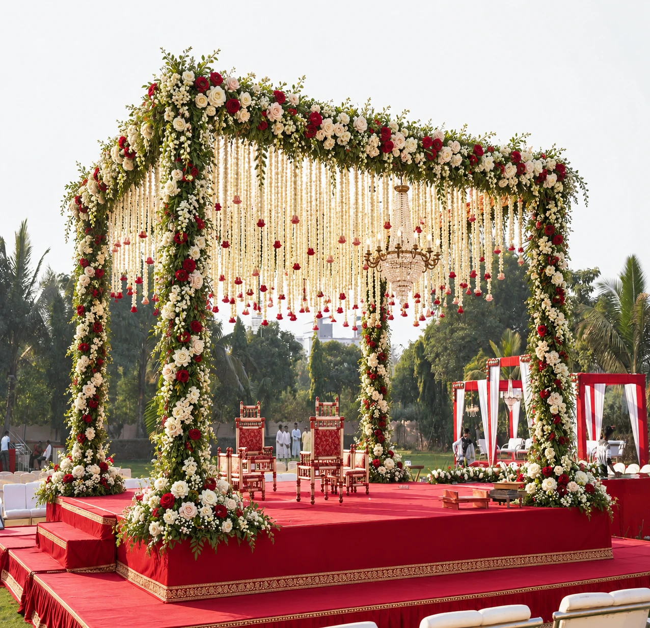 Open-air floral mandap with hanging garlands and a red ceremony platform